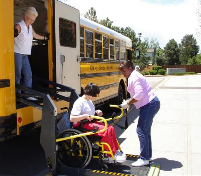 Student in a wheelchair using a lift to get on a bus. Student in a wheelchair using a lift to get on a bus.